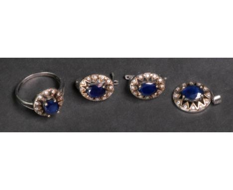 A sapphire and white stone set silver pendant, ring and earring suite; each set with an oval cut sapphire, claw-set to a surr