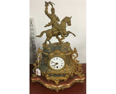 A late 19th century French gilt metal mantel clock having a convex enamel dial with Roman numerals and 30 hour movement, surm