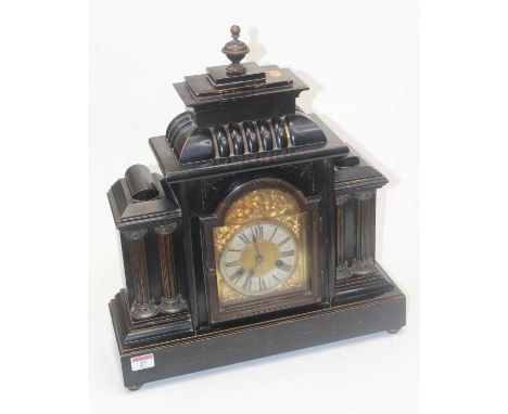 A late 19th century Continental faux black slate cased mantle clock of architectural form, having an arched brass dial with e