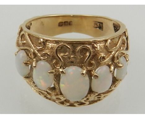 A yellow metal and graduated five stone opal ring, having elaborately decorated shank. 