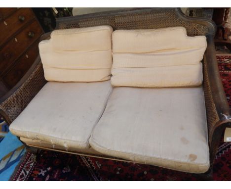 A 20th century mahogany framed bergere style sofa, W: c150cm, together with matching armchair, double caned with carved arms 