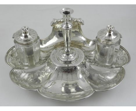 A Victorian solid silver desk stand, London 1856, the stand of shell form, comprising two silver topped glass wells and taper