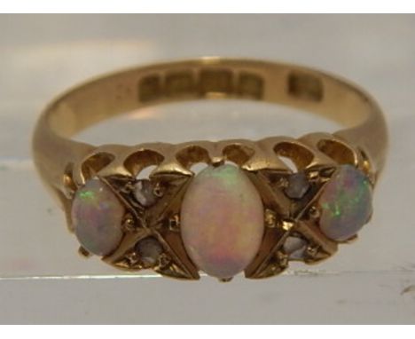 An 18 carat yellow gold, diamond, and opal ring, set three oval cut opals interspersed with diamonds. 