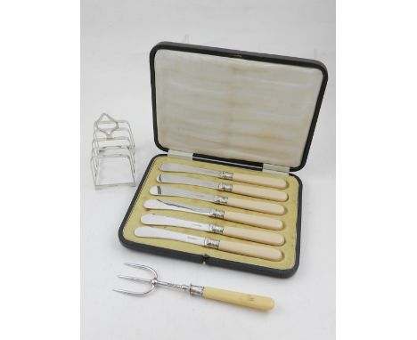 A cased set of six breakfast knives, together with a Victorian silver toast fork, hallmarked Sheffield 1900, and a silver toa
