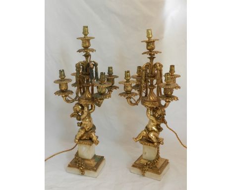 A pair of gilt metal five light candelabra table lamps, having four acanthus decorated arms, supported on cherub figure colum