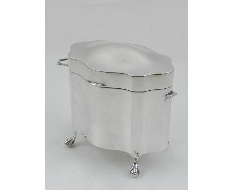 An Edwardian silver tea caddy, Chester 1908 by Blanckensee, with handle to each side, raised on four paw feet, 
