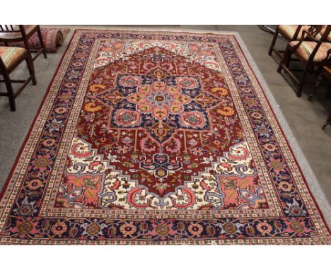 An Eastern carpet, having central lozenge shaped medallion within stylised multi borders on a predominately red and blue grou