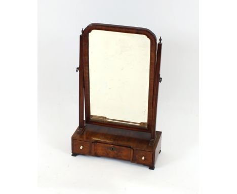 An Antique walnut swing toilet mirror, the bevelled plate in cushioned frame, raised on square reeded arms surmounted by bras