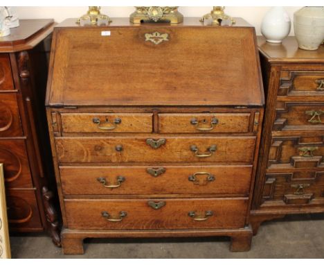 An Antique oak bureau, fitted two short over three long drawers, the fall front opening to reveal an interior of drawers and 