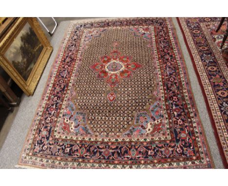 An Eastern carpet, having central stylised floral medallion within geometric multi borders on predominately red, beige and bl