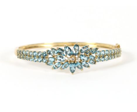 A 9 carat gold snap bangle, set with faceted pale blue stones