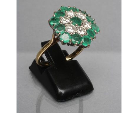 AN EMERALD AND DIAMOND CLUSTER RING, the flower panel point set with six brilliant cut diamonds and thirteen facet cut emeral