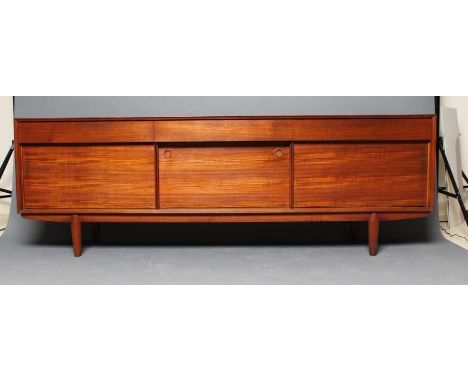 A MID CENTURY DESIGN TEAK LOW SIDEBOARD, the fascia with three frieze drawers, the centre one fitted for cutlery, three reces