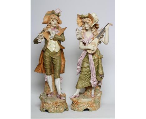 A LARGE PAIR OF ROYAL DUX FIGURES, early 20th century, both in lace trimmed 18th century garb, the young male playing a flute
