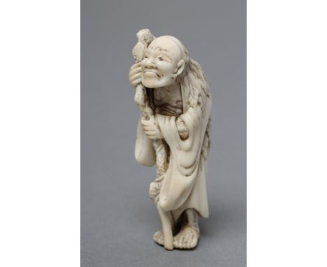 A JAPANESE IVORY NETSUKE, Meiji period, the Tekkai Sennin resting on his gnarled staff, unsigned, 2" high (Est. plus 21% prem