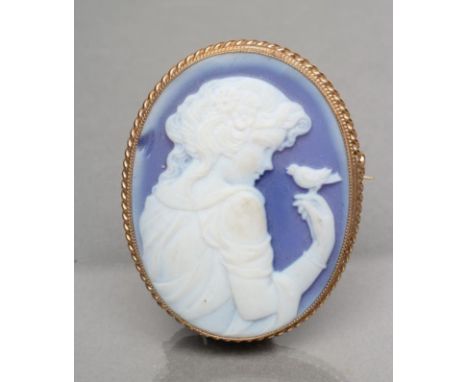 A 9CT GOLD MOUNTED CAMEO BROOCH, the Wedgwood blue glass oval panel cut and frosted with a half length portrait of a young gi