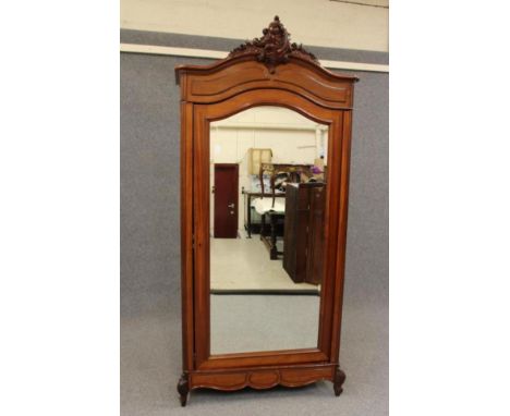 A MAHOGANY ARMOIRE, 19th century, the arched moulded cornice centred by a carved scrolling foliate surmount, the frieze with 