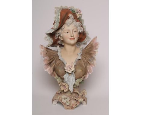 A ROYAL DUX BUST, early 20th century, the young fashionable lady wearing a large brimmed hat and frilled dress, on an encrust