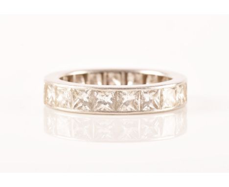 A white metal diamond eternity ring, set with nineteen rectangular princess cut diamonds with an approximate weight of 3.8 ca