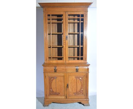 Art Nouveau oak bookcase cabinet, pair of glazed doors above two short drawers and pair of cupboards with carved Art Nouveau 