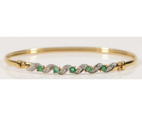 A 9ct gold emerald and diamond twist bangle, hinge at the edge of the panel, 63mm internal, 4.7g
