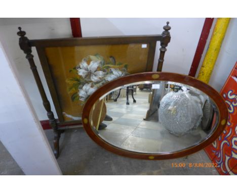 An Edward VII inlaid mahogany oval mirror and an embroidered fire screen 