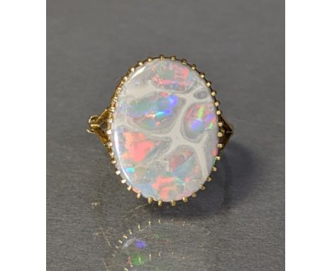 An opal ring, the oval-cut stone approx. 18mm X 14mm, claw-set to a yellow metal shank marked "18ct"; 3.8gm., size: M