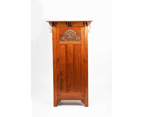 A Shapland and Petter oak wardrobe, the single, hinged door inset with large copper panel stamped in low relief with two bird
