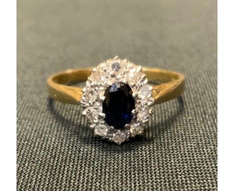 A sapphire and diamond cluster ring, central deep blue oval sapphire approx 0.40ct, ten diamonds, 18ct gold shank, size S/T, 