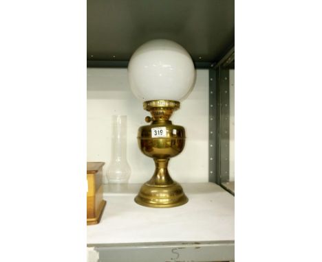 A brass oil lamp with shade and chimney