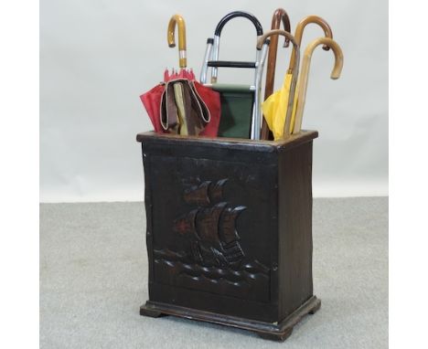 A 1920's oak stick stand, containing various walking sticks and umbrellas