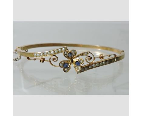 An Edwardian 9 carat gold seed pearl and sapphire set hinged bangle, boxed