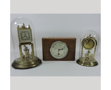 An anniversary clock, contained under a glass dome, 31cm overall, together with another smaller, and a mantle clock