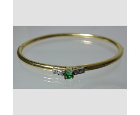 A unmarked hinged bangle, set with a central emerald flanked by diamonds, boxed