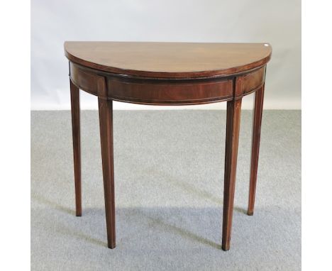 A George III mahogany cross banded and boxwood strung half round folding card table, on square tapered leg, 76cm