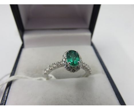 EMERALD & DIAMOND RING, 18ct white gold ring set an oval emerald within a cluster of diamonds with diamond shoulders, size K