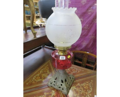 EDWARDIAN OIL LAMP, cranberry glass reservoir cast metal base oil lamp with spherical glass shade