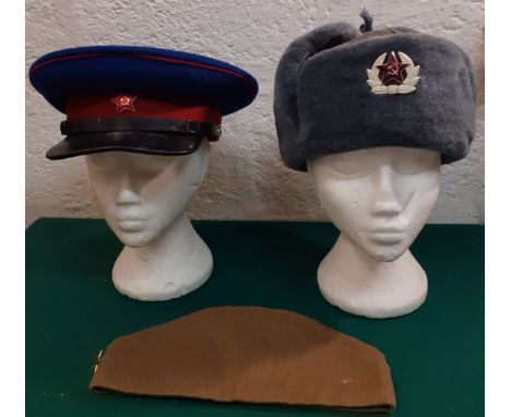 A collection of 3 Russian service hats to include a mid 20th Century USSR NKVD Officer's peaked cap and a Soviet Ushanka Army