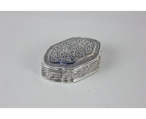 An Eastern white metal snuff box of serpentine form, decorated with two figures amongst scrolling foliage within multiple bor