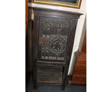 A 17th century style oak cabinet with carved Gothic cupboard door, on rectangular supports with shelf beneath, 59cm