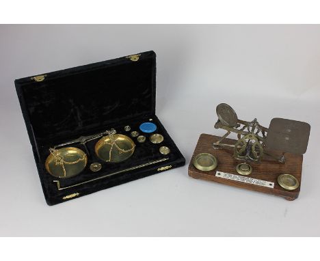 A set of apothecary scales and weights in fitted case, together with a set of brass postal scales mounted on oak base, with a