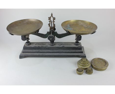 A set of cast iron kitchen scales marked 'Force 5 kilog', 40cm, with two circular brass pans and a selection of weights