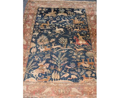 A Qum handmade wool carpet,decorated with a Shekari hunting scene on a dark blue ground, within a gold border, 200 x 140cm