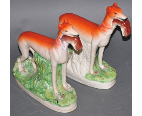 A pair of 19th century style Staffordshire hunting dogs, each holding a rabbit, H. 28cm, (2)