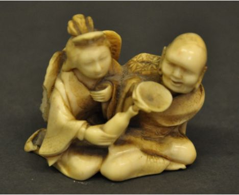 A Japanese 19th century ivory netsuke of a finely carved elderly couple, the winged lady holding a bottle and the man drinkin