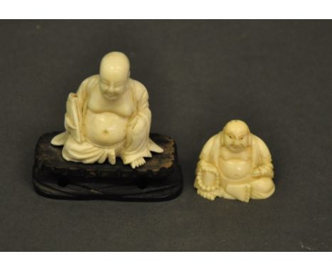 Two late 19th century/ early 20th century ivory Buddhas. One Chinese and one Japanese, one seated on a carved hardwood stand 