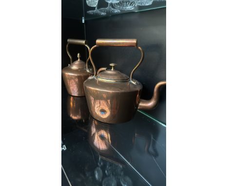 Pair of vintage copper kettles with brass fittings and curved spouts. Elegant design with classic charm.