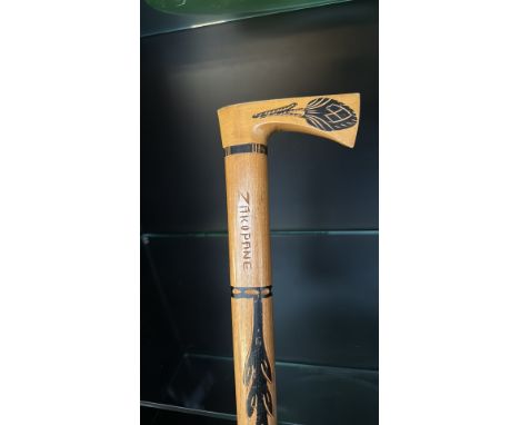 Hand-carved wooden walking stick with an intricately engraved axe-shaped handle, decorated with traditional folk motifs and m