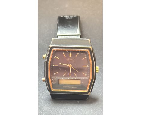 Vintage Seiko Quartz Alarm Chronograph wristwatch features a black and gold-tone case and a rectangular dial with a dual anal