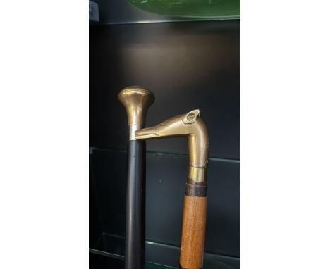 Two vintage walking canes, one with a brass dog's head handle and wood shaft, the other with a rounded brass handle and black